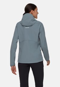 Giacca softshell grigio chiaro con cappuccio, dotata di un logo sulla schiena, progettata con una forma aderente e una texture liscia.