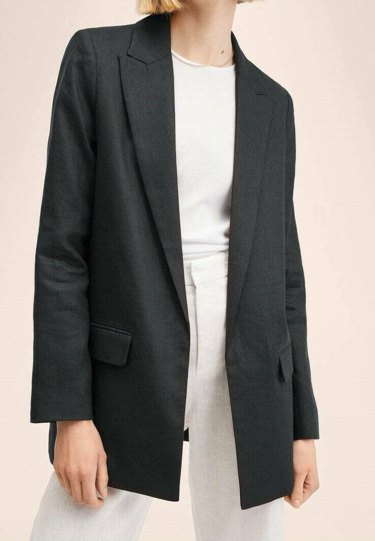 Černý blazer vyrobený z texturované látky, s jedním knoflíkem, dvěma předními kapsami a uvolněným střihem. Nositý přes bílou košili.