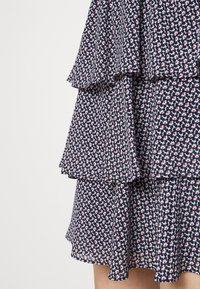 Abito navy con rouches sovrapposte, caratterizzato da una stampa floreale in rosso e bianco. Tessuto morbido con una texture leggera e orlo irregolare.