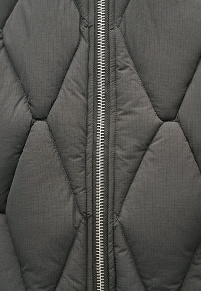 Grå quiltet jakke med et horisontalt diamantmønster, udstyret med en sølvfarvet lynlås og mørke syninger, der viser en glat tekstur.