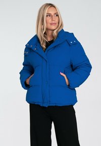 Niebieska ocieplana kurtka z wysokim kołnierzem, przednimi guzikami i bocznymi kieszeniami. Charakteryzuje się gładką fakturą i delikatnym połyskiem.