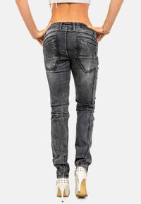 Jeans grigi con vestibilità aderente, cuciture evidenti, design a cinque tasche e una texture leggermente usurata. A vita alta con gamba sagomata.