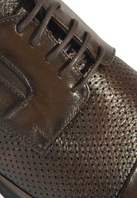 Bruine leren dansschoen met geperforeerde textuur en gladde accenten, voorzien van bruine veters en een ingewikkeld gestikt ontwerp.