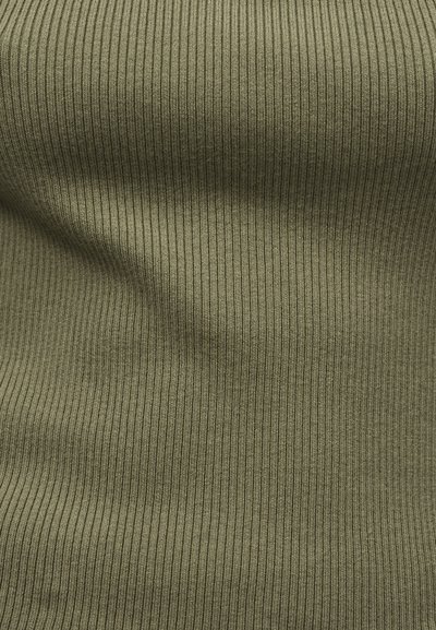 Πλεκτό ύφασμα σε ελιά με ραβδώσεις και κάθετες υφές με διακριτικές πτυχές που δημιουργούν απαλά σκιές και φωτεινές ανταύγειες.