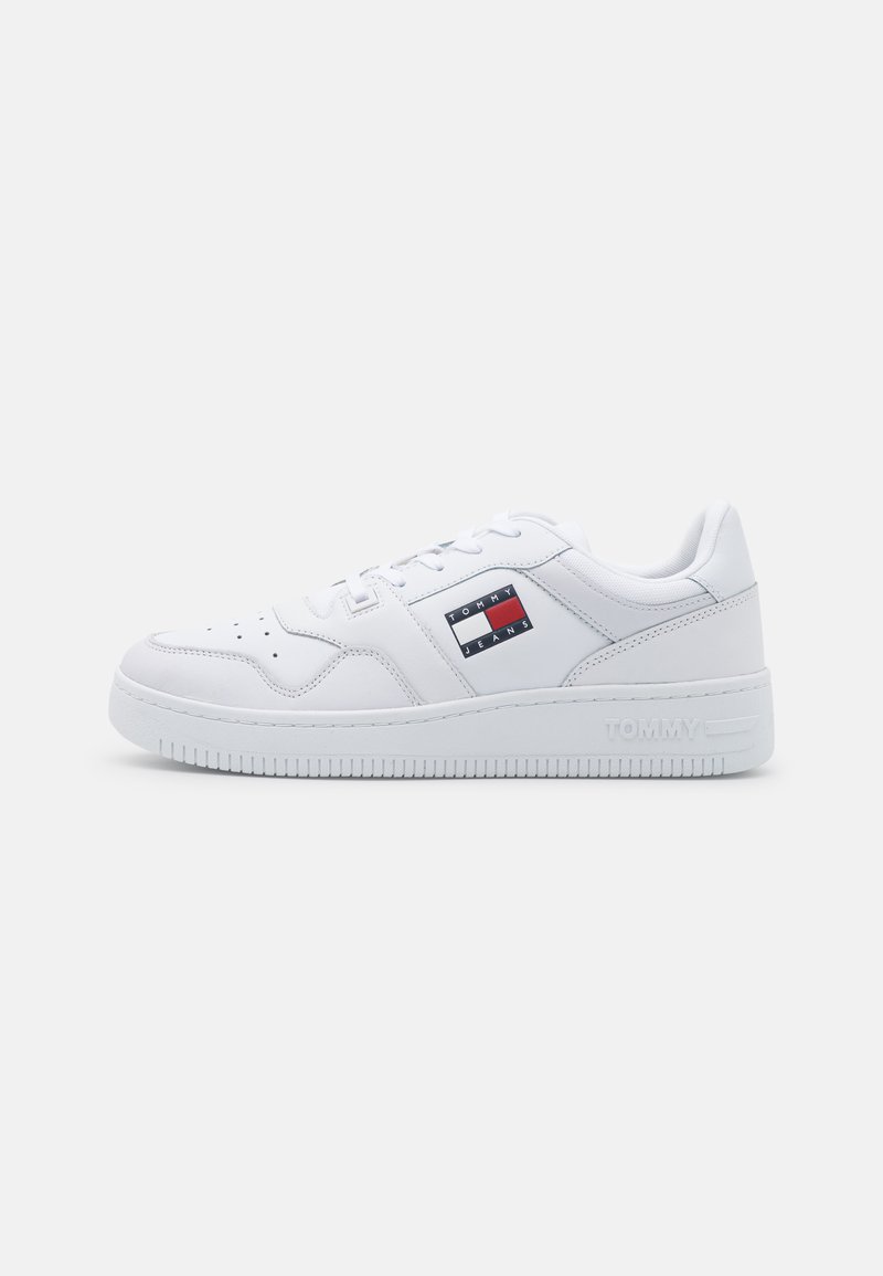 Sneaker bianche con finitura in pelle liscia, dotate di un patch logo rosso, bianco e blu e suola in gomma testurizzata con il marchio "TOMMY".