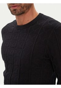 Schwarzer Strickpullover mit strukturiertem Muster und vertikalem Rippstrick, Rundhalsausschnitt, aus weichem, elastischem Material.