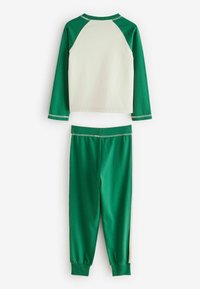Grünes und cremefarbenes Zweiteiler-Outfit bestehend aus einem langärmligen Raglan-Oberteil und schmal zulaufenden Hosen. Hergestellt aus weichem Baumwollmaterial mit elastischem Bund und Bündchen.