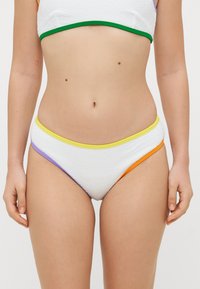 Hvit bikinitruse med teksturert stoff. Utsmykket med lilla, gul og oransje bånd langs livet, med et høyt snitt.