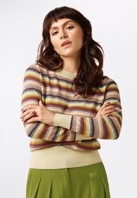 Gestreifter Strickpullover mit Rundhalsausschnitt in Farben wie Beige, Braun, Grün und Gelb. Mit gerippten Bündchen und Saum, kombiniert mit grünen Hosen.