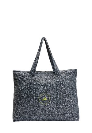 Stor tote taske lavet af tekstureret sort og hvid pletstof med to robuste håndtag; har et grønt logo som accent.