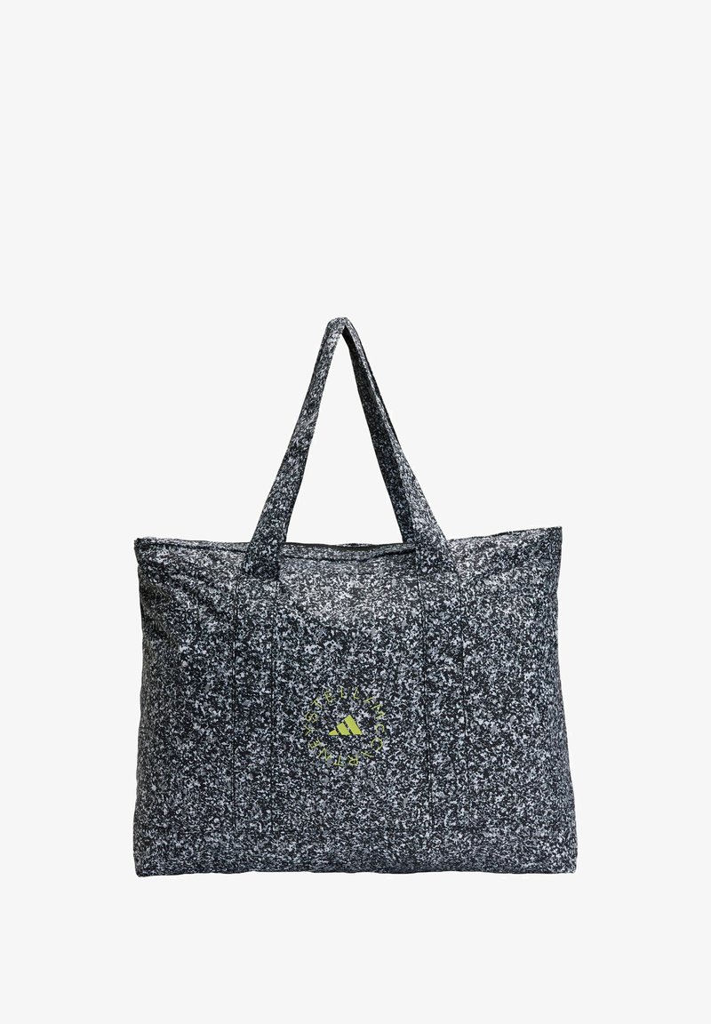 Velika torba od teksturirane tkanine s crno-bijelim speckled uzorkom i dva čvrsta ručka; sadrži zeleni logo akcent.