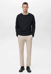 Black long-sleeve shirt with a white inner collar, beige pants, and black shoes. Simple design, regular fit, smooth texture.