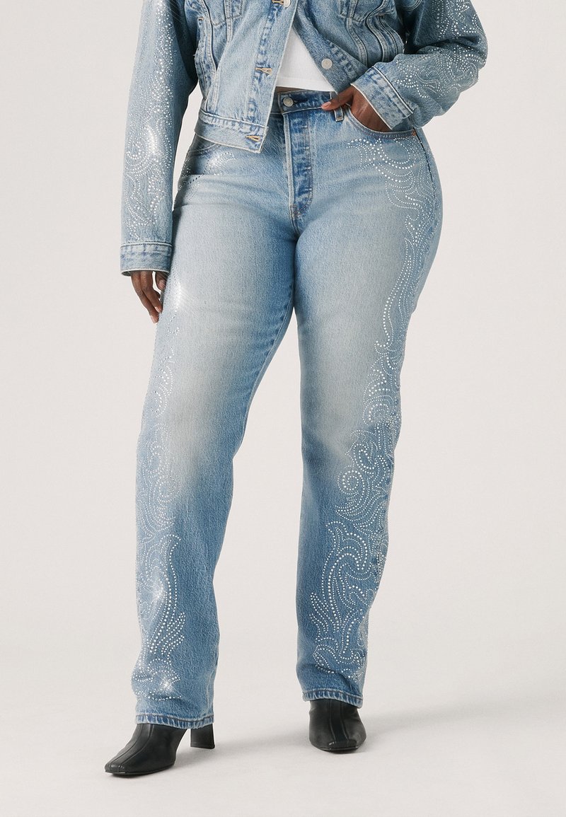 Jeans en denim bleu clair avec un motif orné de strass le long des coutures latérales, coupe droite et taille haute.