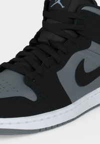 Κοντινή λήψη μαύρου και γκρι ψηλού αθλητικού παπουτσιού με μαύρα κορδόνια, λογότυπο Nike στο πλάι και λογότυπο Jumpman στη γλώσσα.