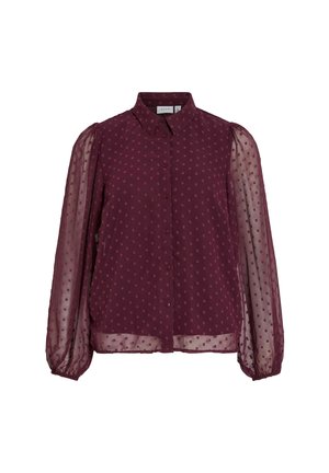 Burgunderbluse med krage, knappestolpe foran og gjennomsiktige pufferm. Har et prikkete mønster og elastiske mansjetter. Myk, lett stoff.