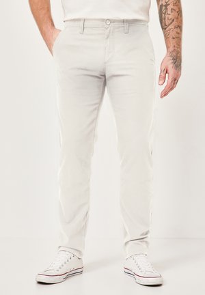 Light grey cotton chinos with a straight-leg cut, featuring side pockets and a buttoned waistband. Paired with white sneakers.