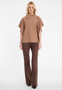 Brown, short-sleeve top with wide sleeves, paired with brown, flared pants and black heels. Smooth fabric with a simple design.