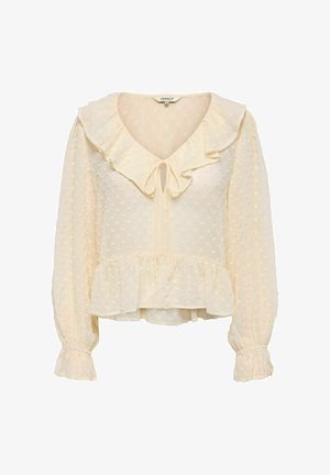 Blouse à manches longues de couleur crème avec des pois texturés, col et poignets à volants, encolure nouée devant et bas à basque.