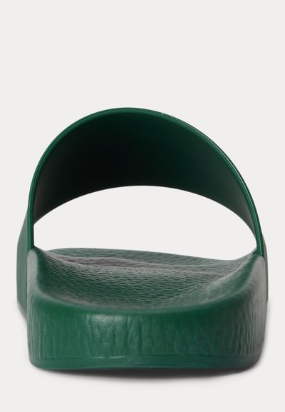 Zöld papucs egyetlen széles pánttal és texturált talpbéléses, elölről fehér háttér előtt látvány.