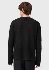Czarny sweter robiony na drutach z długimi rękawami, z teksturowanym wzorem i luźnym krojem. Tył ma okrągły dekolt oraz minimalne detale.
