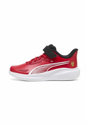 Rød atletiksneaker med hvid sål, sort indvendig polstring, sort velcrorem, røde snørebånd, hvid side stribe og Ferrari-logo på hælen.