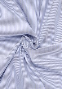 Tessuto a righe blu e bianche con sottili linee verticali, caratterizzato da una texture liscia e una morbida caduta, disposto in un motivo a spirale.