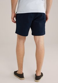 Shorts bleu marine en coton, avec une coupe droite et des poches latérales. Associés à des chaussures décontractées noires à enfiler avec un accent en jute.