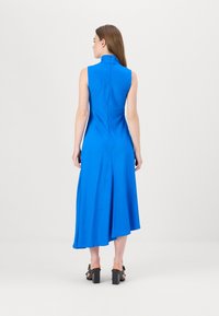 Blaues ärmelloses Kleid mit hohem Kragen und asymmetrischem Saum, aus glattem Stoff gefertigt. Verfügt über ein zentrales Nahtdetail auf der Rückseite.
