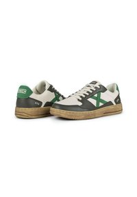 Sneaker con una tomaia in pelle bianca e verde scuro, caratterizzate da un logo verde in accentuazione, sezioni testurizzate in verde scuro e una suola in gomma marrone.