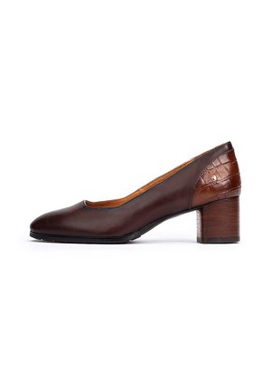 Pompe pour femmes en cuir marron foncé, à bout rond, avec un talon épais et un détail en relief en motif crocodile sur le contrefort du talon.