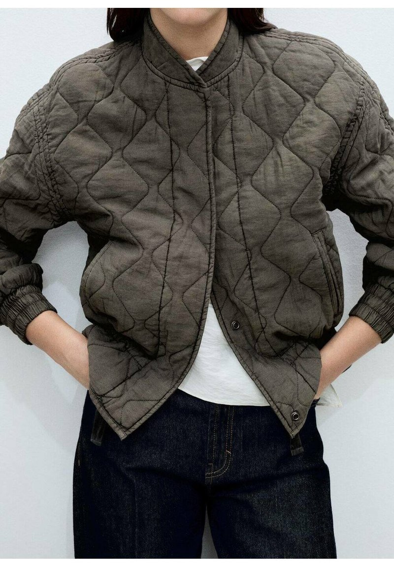 Prešívaná bomber bunda v tmavej olivovej farbe, s vystuženým golierom, ribovanými manžetami a diagonálnym prešívaním. Súčasťou sú dve bočné vrecká.