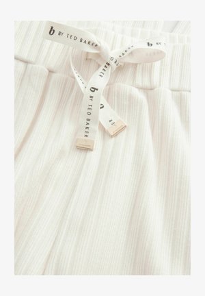 Valkoiset ribattut kangaspajamahousut, joissa on tekstuuripinta. Varustettu vastaavasta kankaasta valmistetulla nauhalla, jossa on kultaiset logot. Vahvistettu elastinen vyötärö.