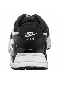 Scarpa sportiva Nike in bianco e nero con tomaia in rete, colletto imbottito e tacco nero lucido con il marchio "NIKE AIR".