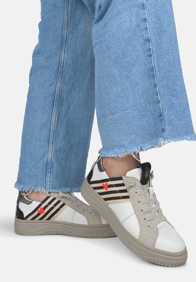 Weiße und beige Sneaker mit schwarzen Streifen und einem roten Herzdetail. Strukturierter Oberstoff mit einer Mischung aus Stoff- und Synthetikmaterial. Flache Gummisohle.
