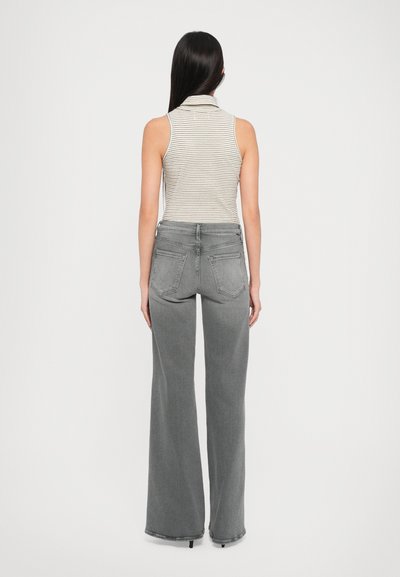 Gray wide-leg jeans with two back pockets, paired with a light gray and white striped sleeveless top with a collar.