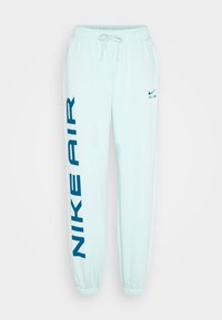 Světle modré tepláky s pasem na šňůrku, elastickými manžetami a výrazným námořnickým logem "NIKE AIR" na levé nohavici. Hladký povrch.