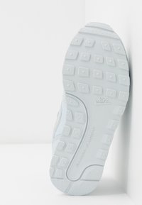 La suola delle sneaker Nike, principalmente di colore azzurro chiaro e bianco, presenta un motivo testurizzato con battistrada rettangolari e circolari, contrassegnata con "non lasciando segni".