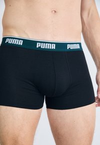 Schwarze Baumwoll-Boxershorts mit einem taubblauen und weißen Markenbund. Das Design bietet eine enge Passform und eine glatte Textur. Keine sichtbaren Muster.