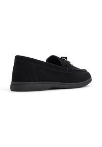 Scarpe slip-on in suede nero con suola in gomma bassa e dettaglio decorativo a forma di fiocco nella parte anteriore. Texture liscia e design classico.