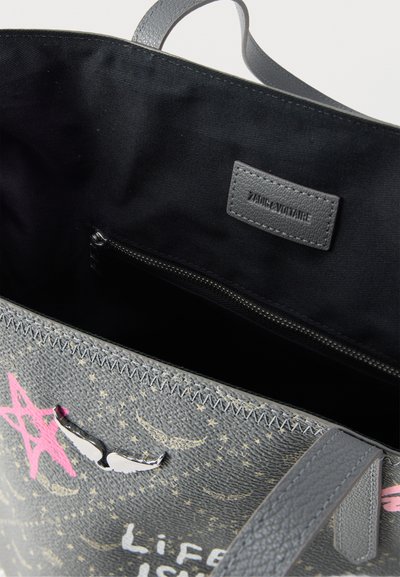 Γκρι δερμάτινη τσάντα tote με ροζ αστερί και στολίδια φτερών, μαύρο εσωτερικό, τσέπη με φερμουάρ και ετικέτα "Zadig & Voltaire".