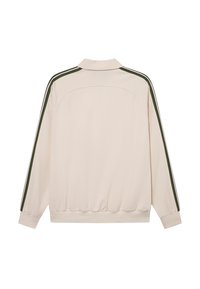Light beige jacket with long sleeves, ribbed cuffs, and waist. Features green stripes along the sleeves. Smooth texture, sporty design.