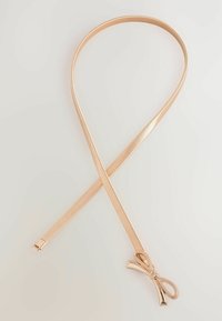Goldfarbene Metall-Haarbinde mit glatter, glänzender Oberfläche, die an einem Ende eine Schleifen-Detail aufweist. Gerades, flexibles Design und schlanke Form.