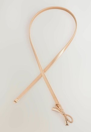 Zlatý kovový vlasový stužka s hladkým a lesklým povrchom, s detailom mašle na jednom konci. Priamy, flexibilný dizajn a štíhly profil.