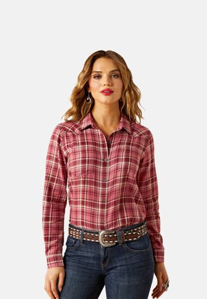 Red plaid button-up shirt with long sleeves and a collar, featuring two chest pockets and denim jeans with a decorative belt.