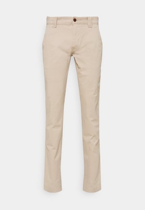 Pantalon beige à jambes droites avec passants de ceinture, bouton frontal et poches latérales, présenté sur un fond clair uni.