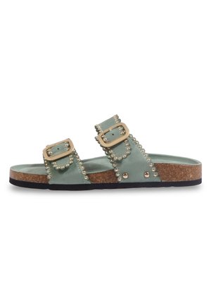 Sandale mule en daim vert avec deux brides réglables à boucle, décorée de clous dorés, semelle en liège et semelle extérieure en caoutchouc noir.