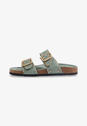 Sandale mule en daim vert avec deux brides réglables à boucle, décorée de clous dorés, semelle en liège et semelle extérieure en caoutchouc noir.