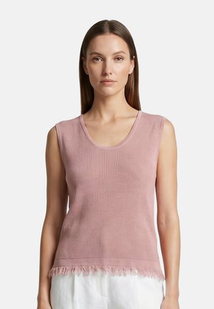 Donna che indossa un top senza maniche in maglia rosa con scollo rotondo e dettaglio con frange sull'orlo, abbinato a pantaloni bianchi.