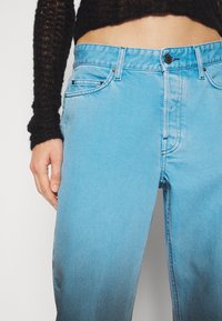 Světle modré džíny z denimu s mírným gradientním efektem, s knoflíkovým zapínáním, designem se pěti kapsami a jemnými detaily v šití.