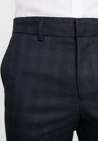 Marineblauwe geruite broeken van een textuurstof, met een platte voorkant, riemlussen en een getailleerde pasvorm.